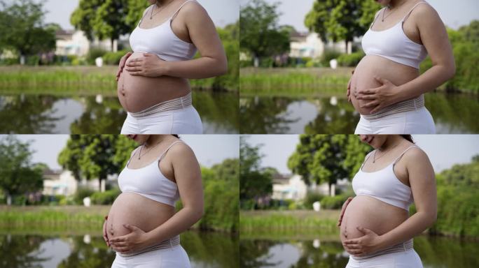 准妈妈孕妇在花园抚摸大肚子特写