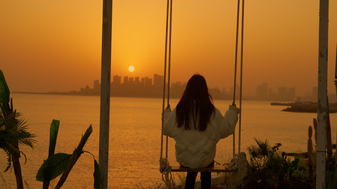 女孩海边荡秋千，看夕阳落日