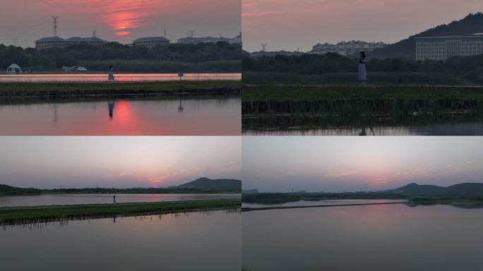 女生在湖中小道上欣赏日落夕阳晚霞绝美风景