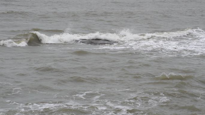 海浪拍打岩石浑浊海水冲刷礁石浪花阴天大海