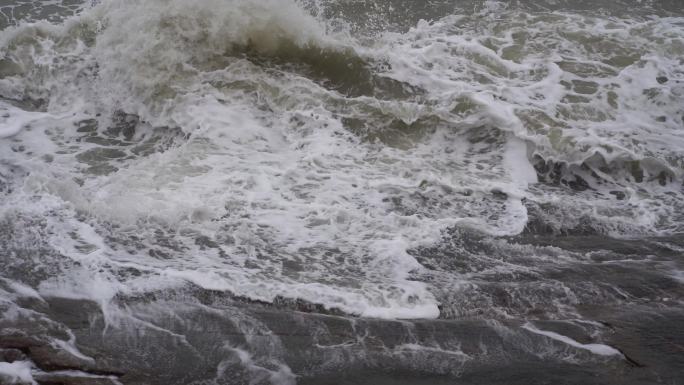 海浪拍打岩石浑浊海水冲刷礁石浪花阴天大海