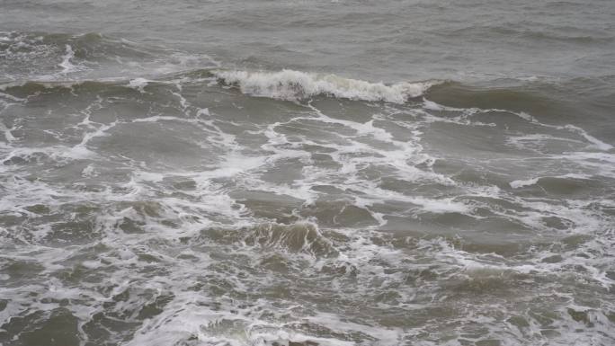 海浪拍打岩石浑浊海水冲刷礁石浪花阴天大海