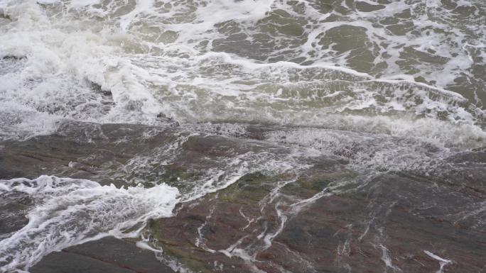 海浪拍打岩石浑浊海水冲刷礁石浪花阴天大海