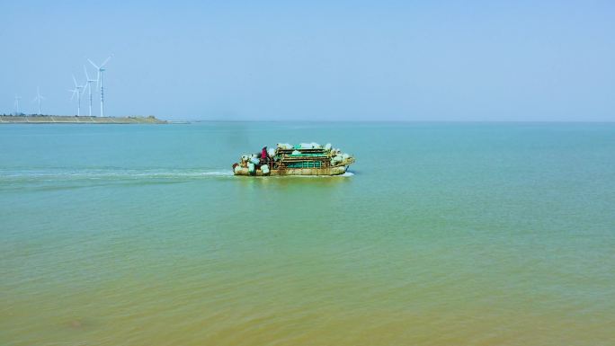 航拍渔民迎着海风驾船在黄海边捕鱼