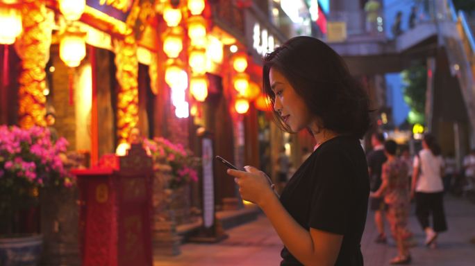 成都夜晚街头美女开心微笑看手机游览旅游