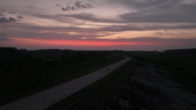 晚霞下男生行走在小村江堤小路上治愈系风景