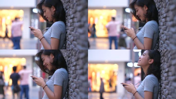 美女在傍晚城市街头开心微笑看手机