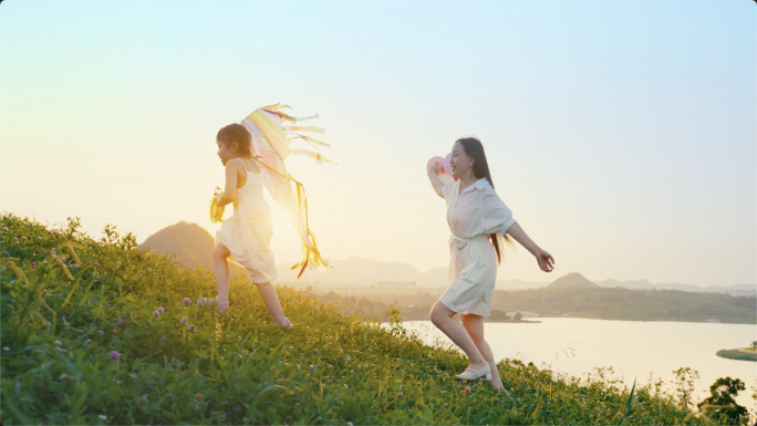 妈妈陪着女孩草地放风筝快乐奔跑度假踏青美