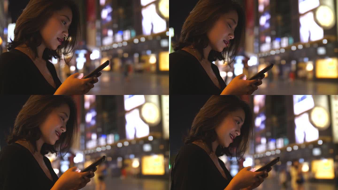 美女商人夜晚城市街头使用手机