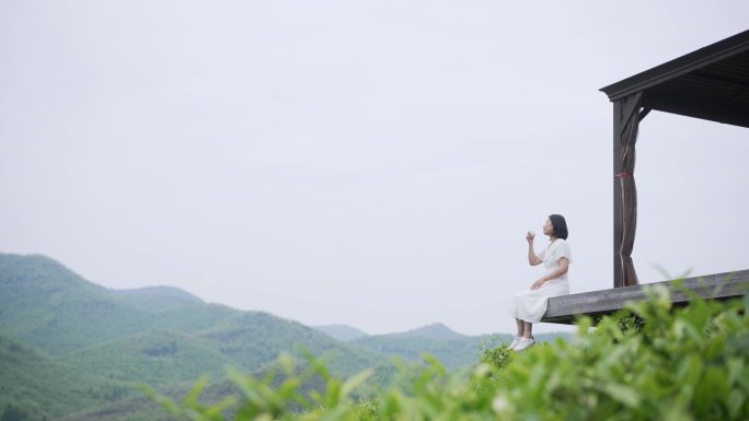 美女坐在茶山亭子喝茶