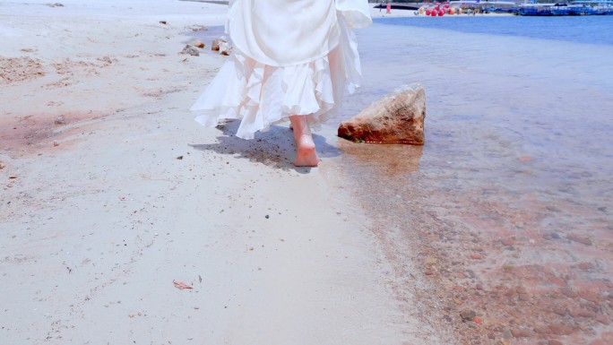 海边沙滩上光着脚丫行走在浅滩的姑娘