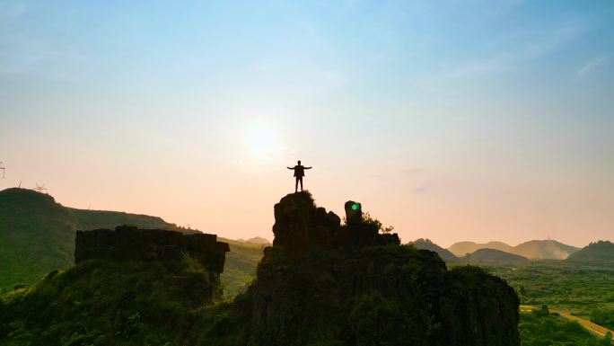 男人登顶山峰张开双臂拥抱太阳追求自由蓝天