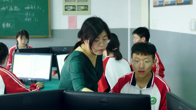 老师在电脑前辅导学生操作