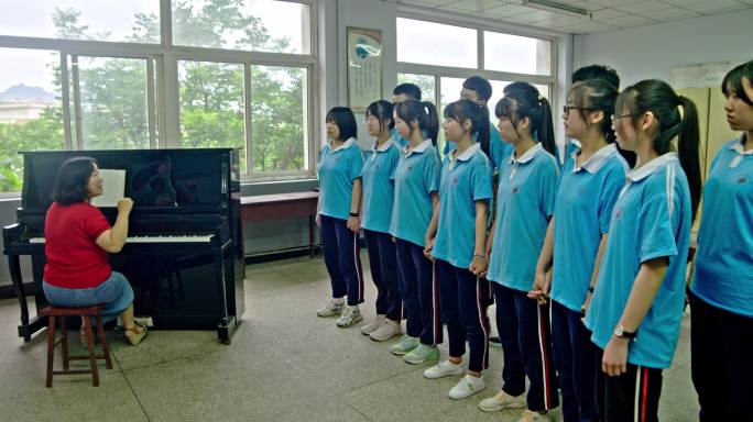 音乐老师弹奏钢琴辅导学生大合唱