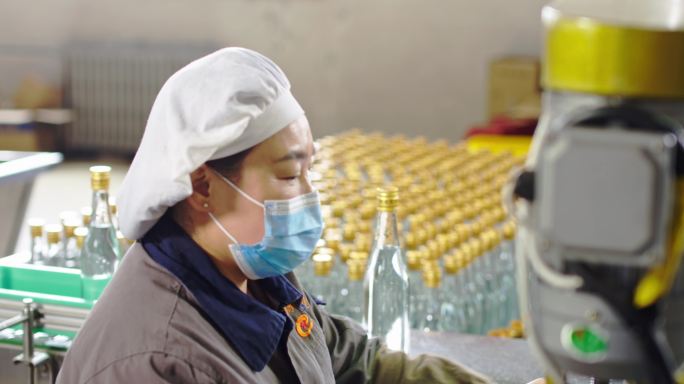 流水生产线上操作罐装白酒设备的女工人