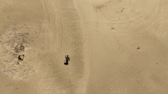 航拍男人行走在塔克拉玛干沙漠中