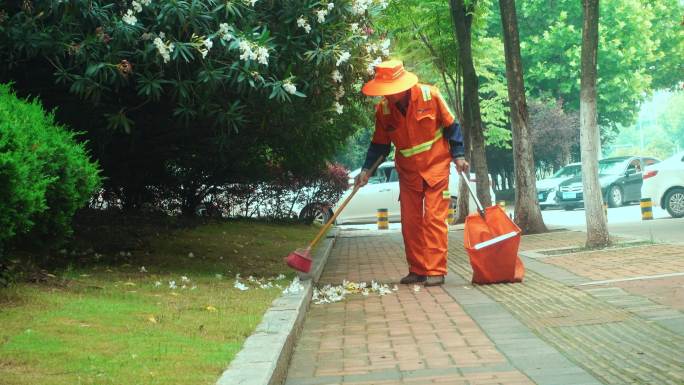 环卫工人在人行道清理落败的花朵