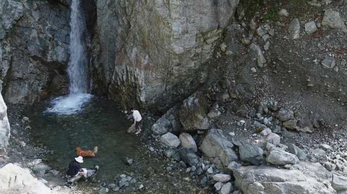年轻人带着宠物犬在山间溪流瀑布玩耍