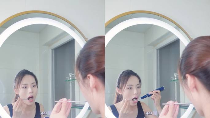 镜子前使用洁牙仪清理口腔的年轻女孩