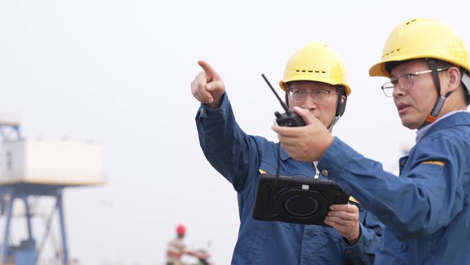 工程师在港口码头拿着平板电脑工作