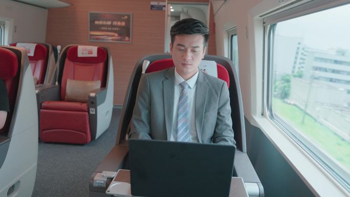 年轻商务男士在高铁上使用笔记本电脑