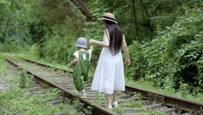 母子大手牵小手妈妈牵着儿子走在铁路轨道上