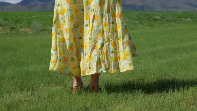 穿着花裙子女孩在绿草地上的脚步