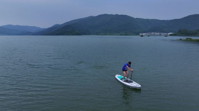 一名男子站在水板上，夏季户外划船