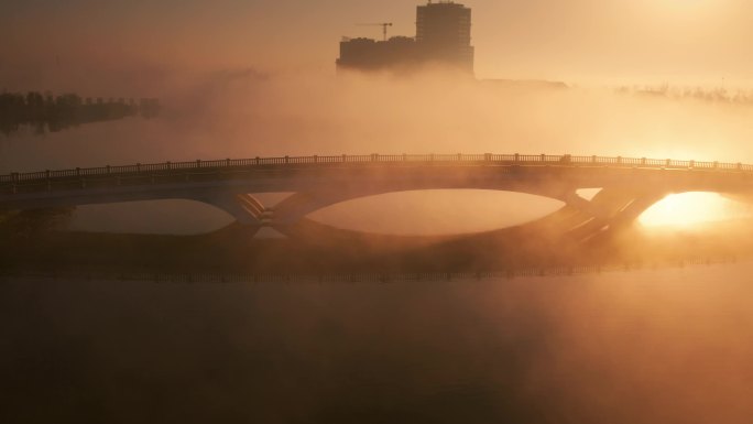 航拍日出晨雾中湖面上的桥梁与交通