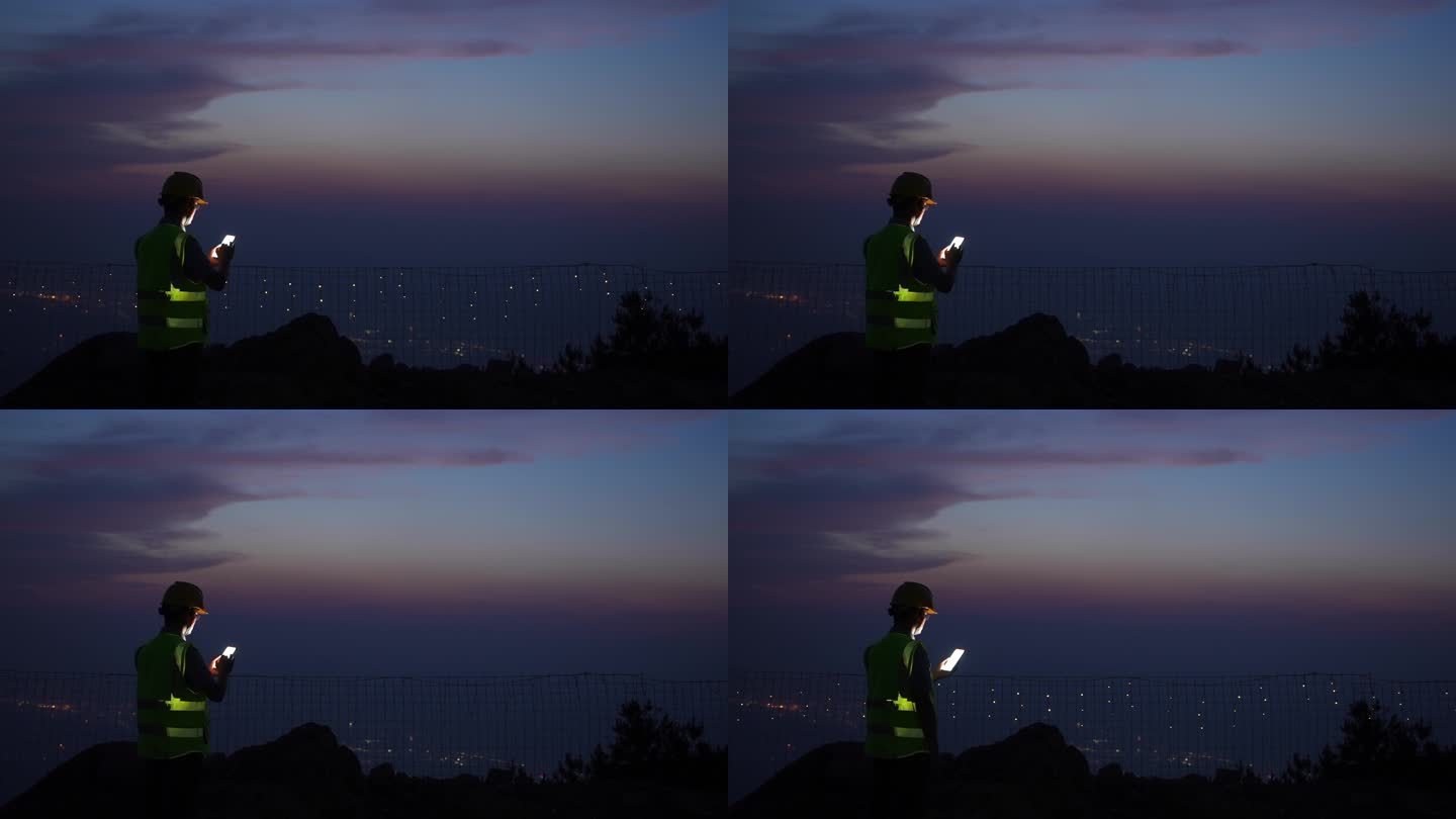 夕阳下工程师在山顶使用手机