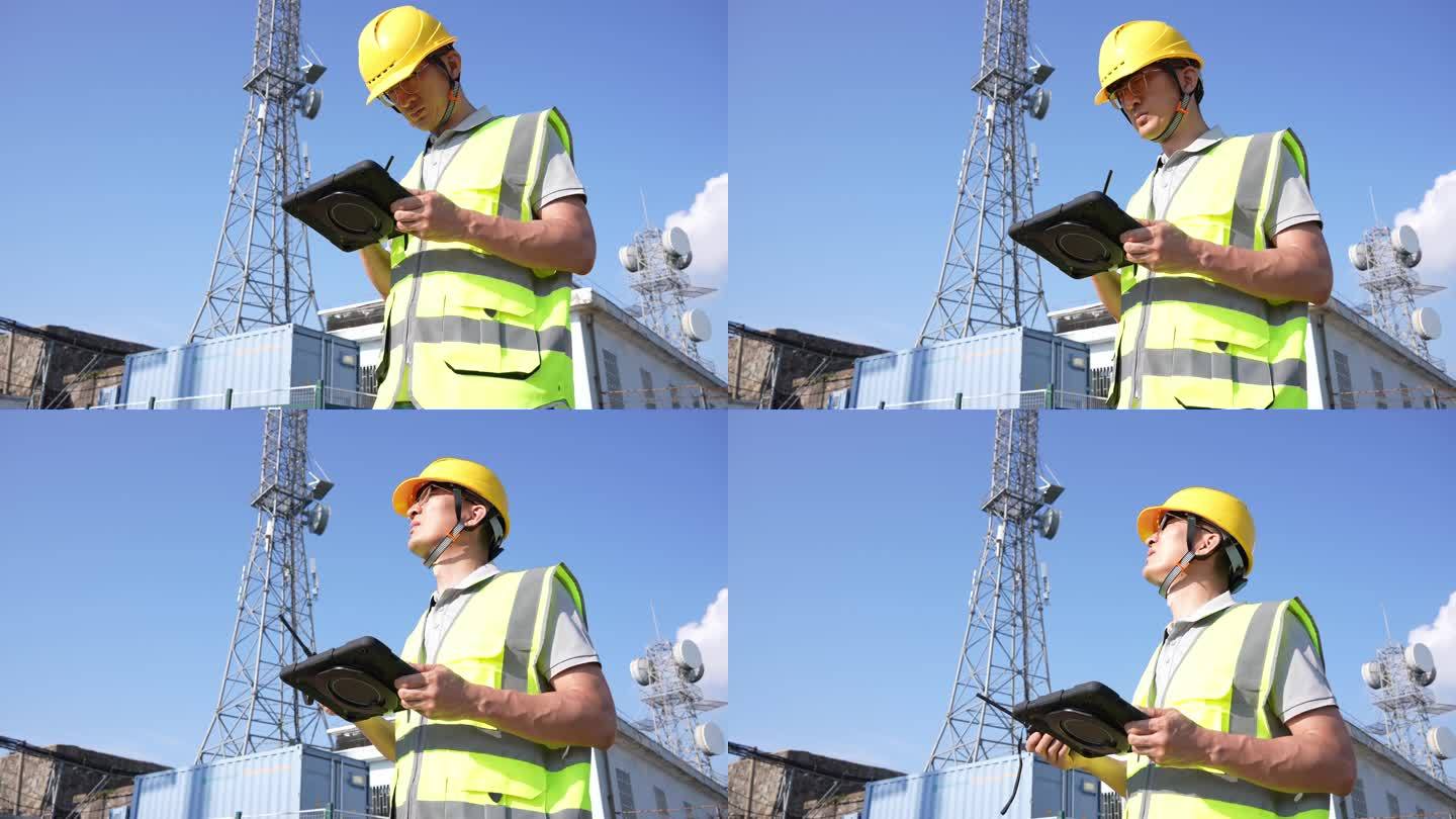 工程师在通信基站铁塔下平板电脑工作