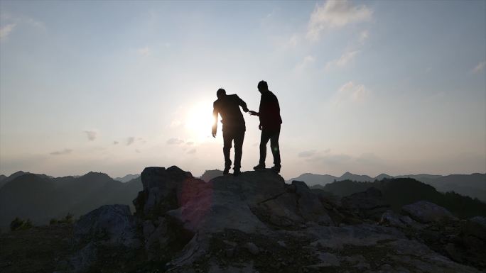 团队手拉手登上山顶举手呐喊拥抱太阳攀登者