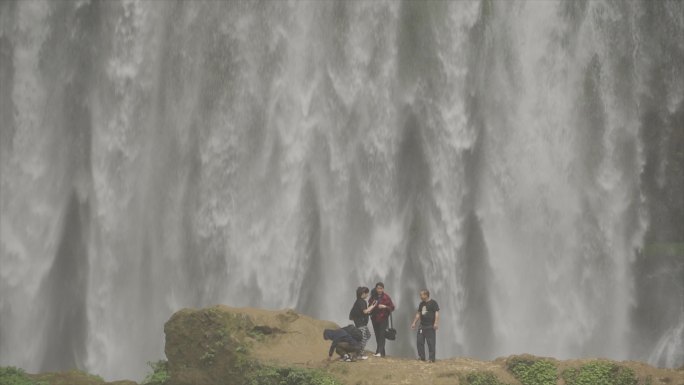 一群人瀑布前拍照打卡户外探险飞流直下溪流