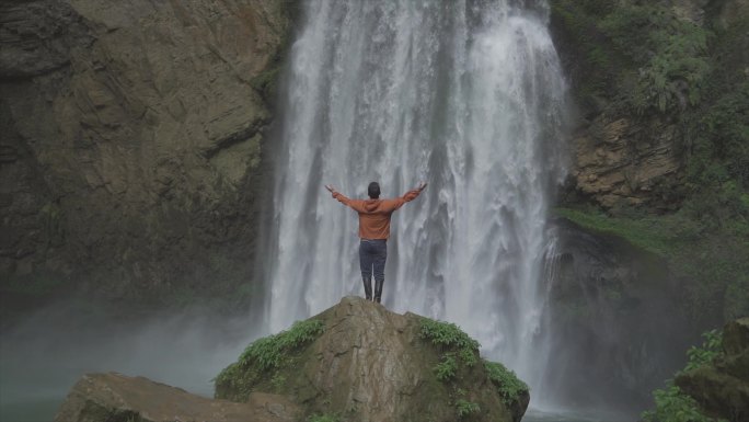 山间瀑布张开双手拥抱大自然徒步爱好者登山