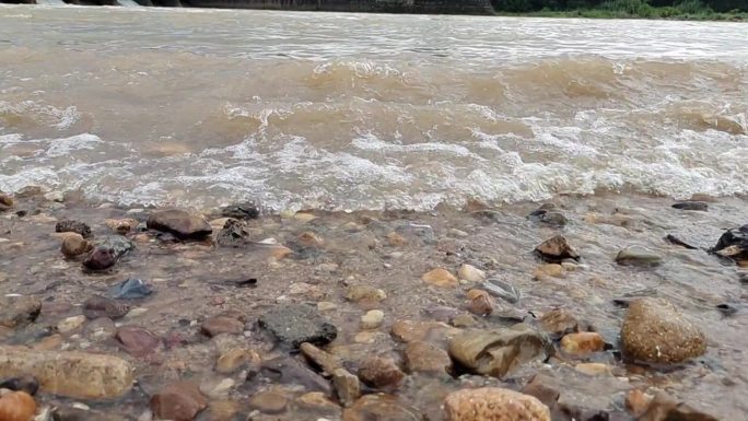河边鹅卵石江水翻滚水浪拍打河水水位上升
