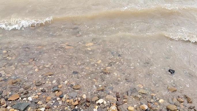 河边鹅卵石江水翻滚水浪拍打河水水位上升