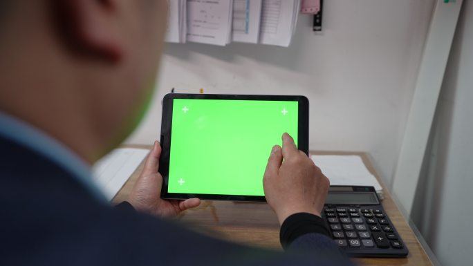 男子低头触屏绿色屏幕的iPad