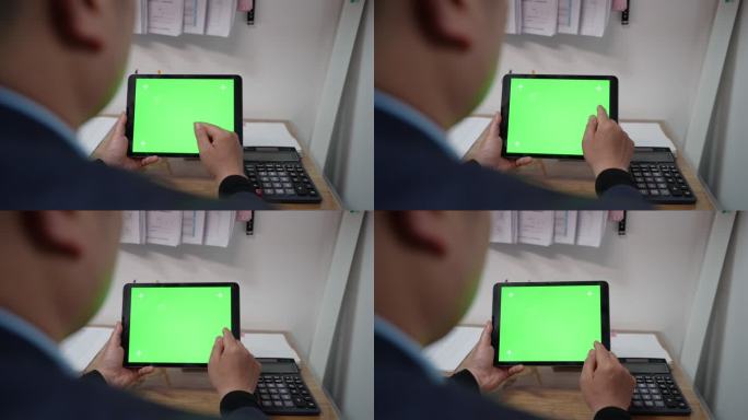 男子低头触屏绿色屏幕的iPad