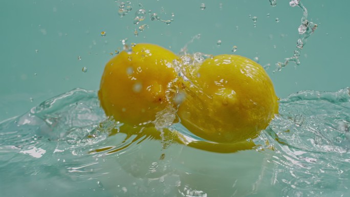 一对柠檬在水面碰撞高速特写柠檬黄柠檬