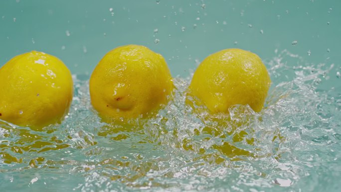 一堆柠檬落在水面水花高速特写柠檬黄柠檬