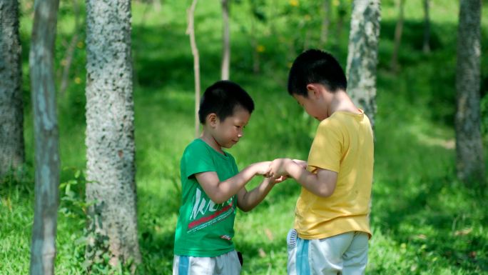 两个小孩在树林里捉虫子 玩蚱蜢 蝗虫