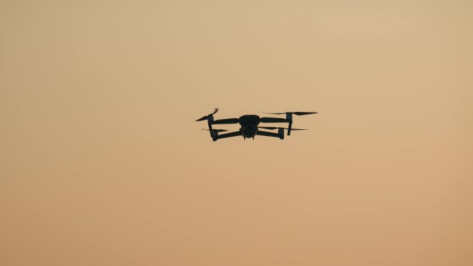 夕阳天空飞翔的无人机航拍器