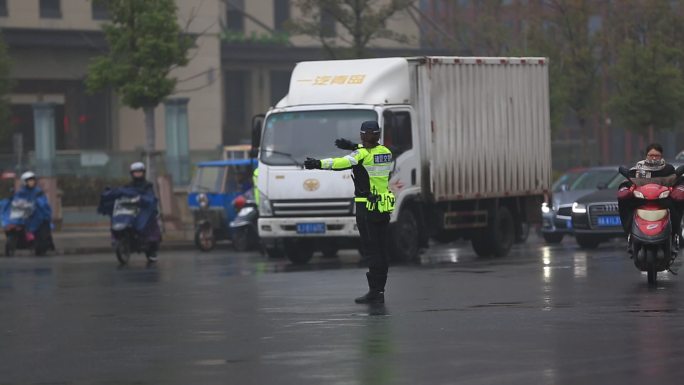 雨天城市道路中间女交警指挥交通车辆通行