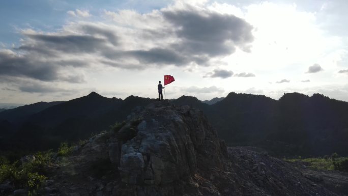 手持国旗站在山顶红色主题教育红旗随风飘扬