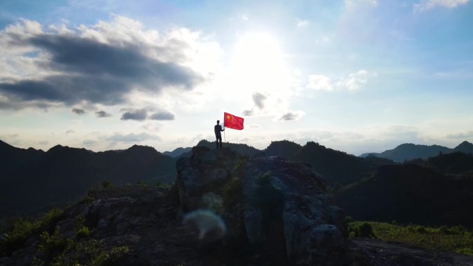 阳光少年手持国旗山顶迎风飘扬爱国主义教育