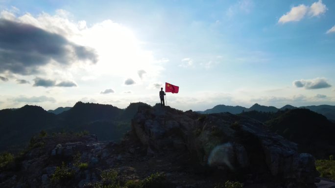 手持红旗站在山顶国旗迎风飘扬爱国教育素材