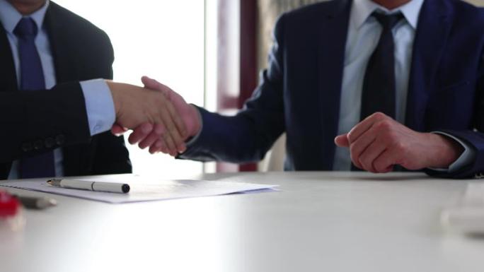 商人分别在合同文件上签字并握手