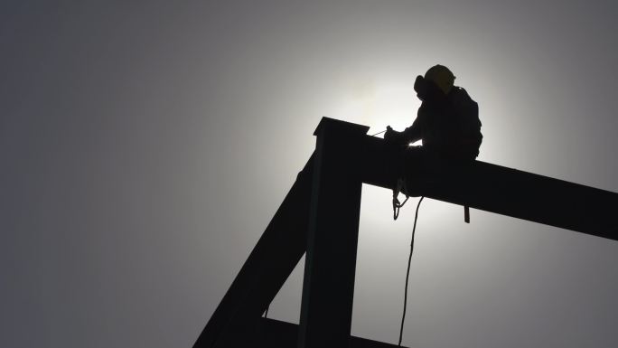 建筑工地焊接工人钢构钢架施工吊装剪影吊机