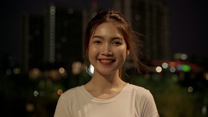 晚上, 在市中心的大街上旅行时, 快乐美丽的年轻亚洲女人对着镜头微笑着感到快乐。生活方式旅游旅游度假