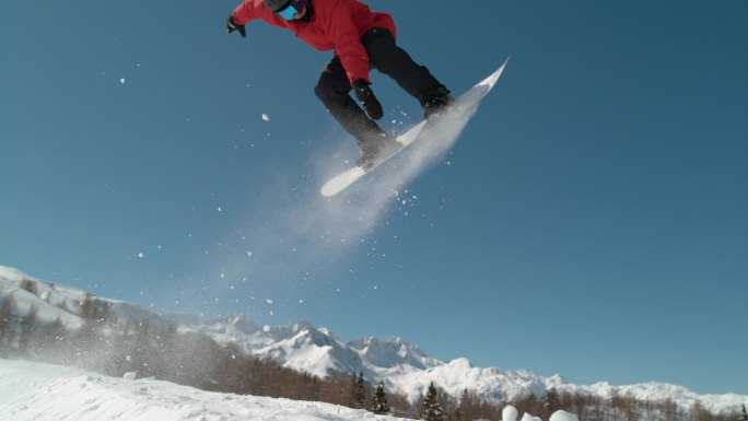 慢动作，特写：赞成滑雪板的人骑到踢腿者的边缘，跳到空中做一个令人敬畏的把戏。 田径男子滑雪板在空中滑